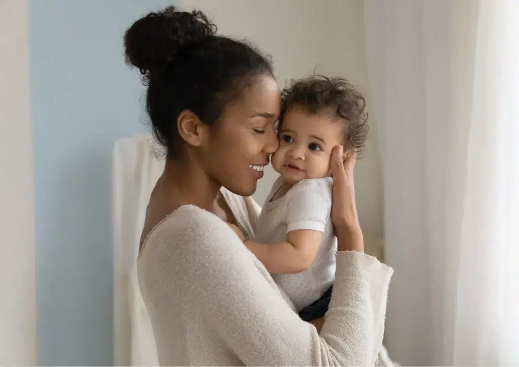 Mom hugging her baby and smiling, showing how to help your baby talk with love and early speech development