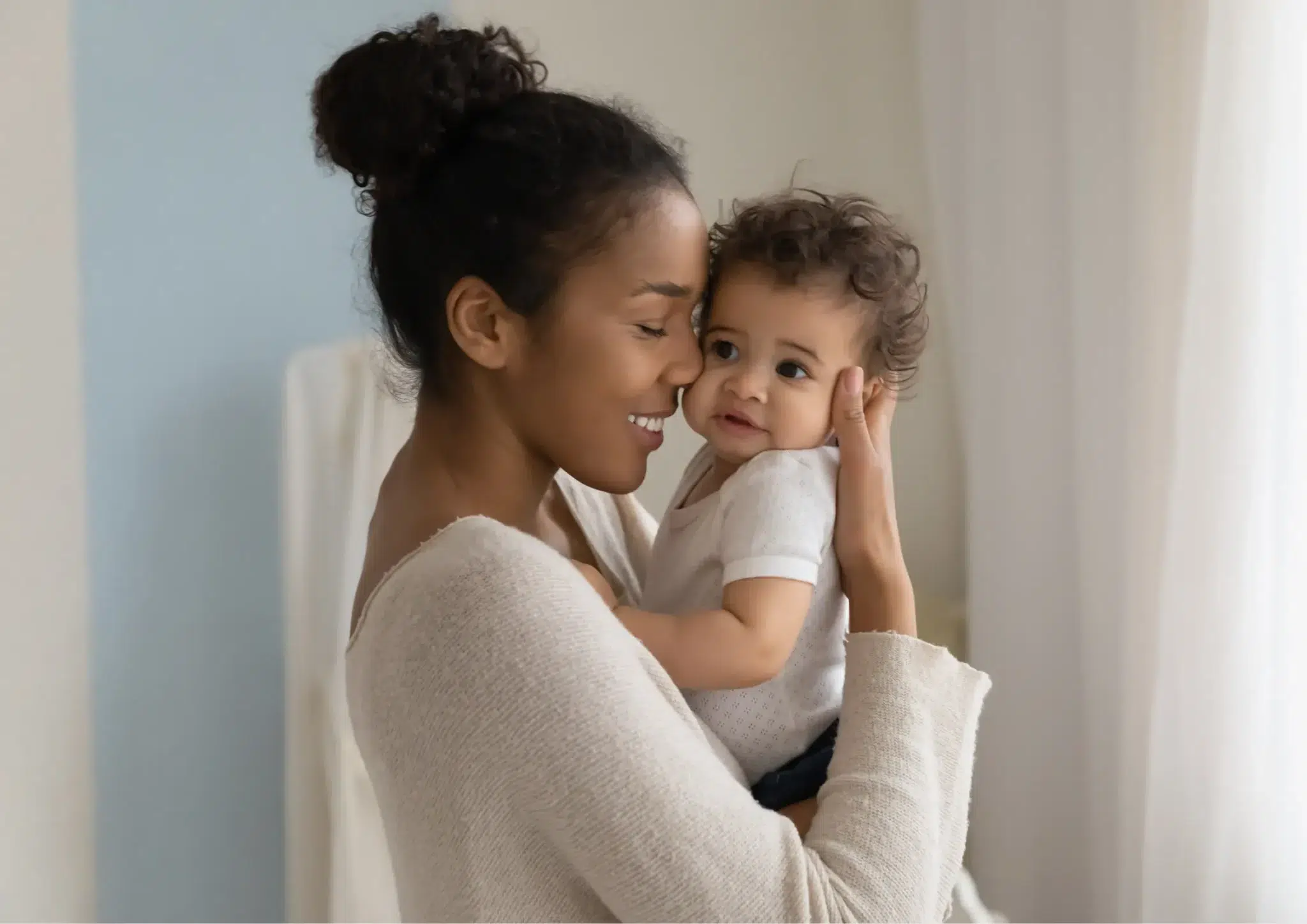 Mom hugging her baby and smiling, showing how to help your baby talk with love and early speech development