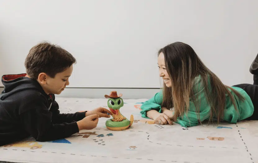 - Child and speech pathologist using a game at floor level during therapy