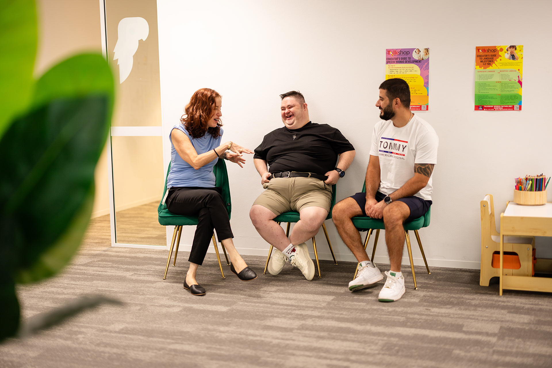 Therapist chatting with two clients in a welcoming clinic space – Speech Pathology Ashfield.
