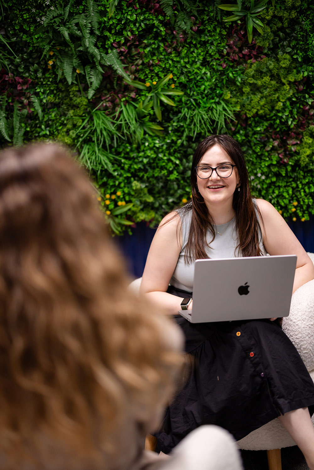 Smiling team member working on a laptop in a calming space – Speech Pathology Ashfield.