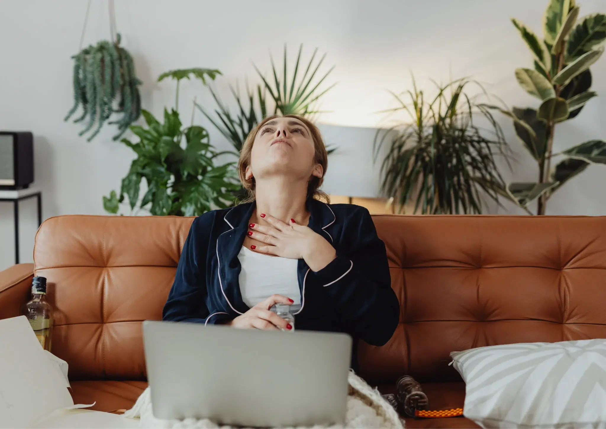 Woman-sitting-on-a-couch-appearing-concerned-while-struggling-to-swallow-representing-symptoms-of-dysphagia