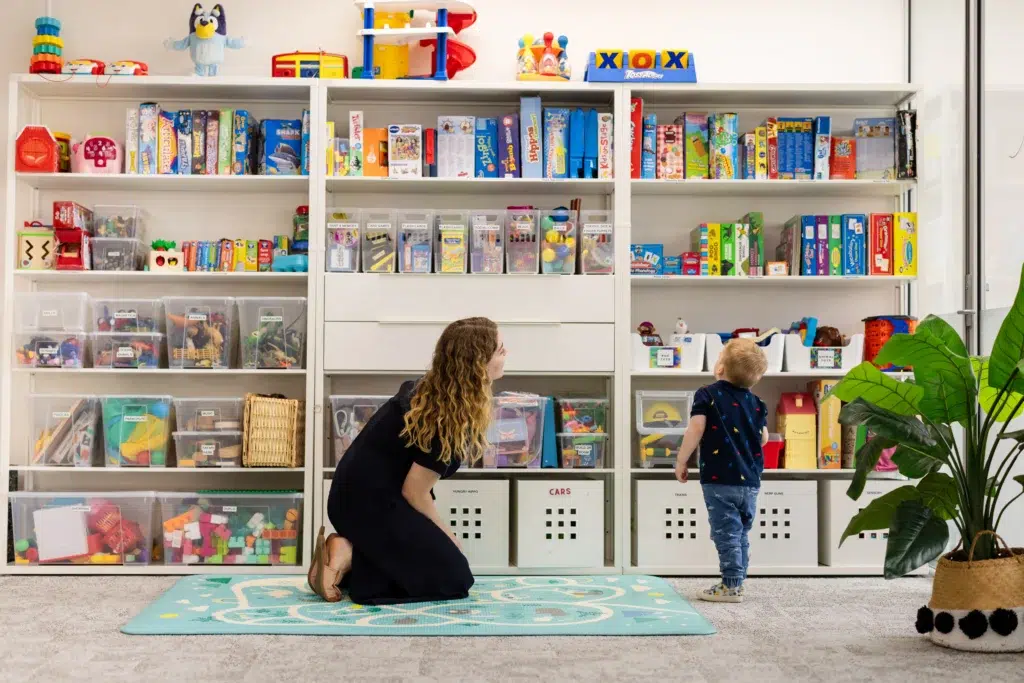 Speech pathologist providing speech therapy to a young boy in the clinic with toys during a speech therapy session