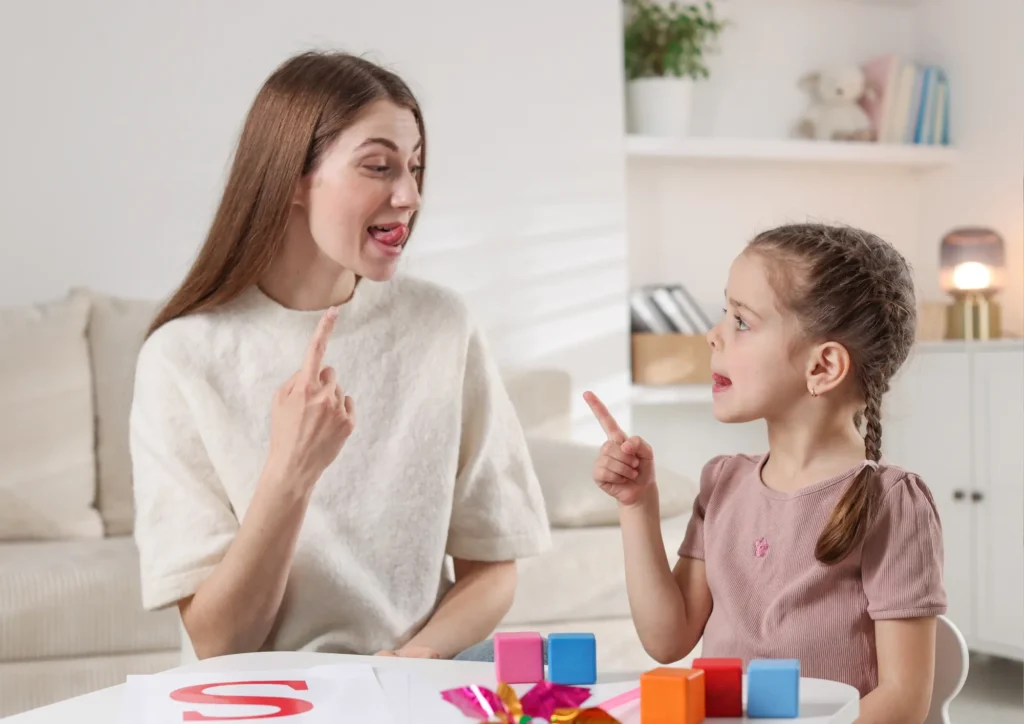 Speech therapist helping a little girl with tongue exercises during a dysarthria speech therapy sessions