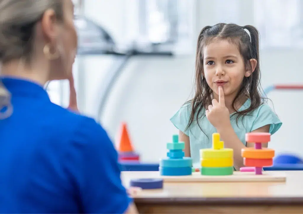 Speech pathologist and young girl playing with blocks during dysphonia speech therapy session to support voice and communication skills.