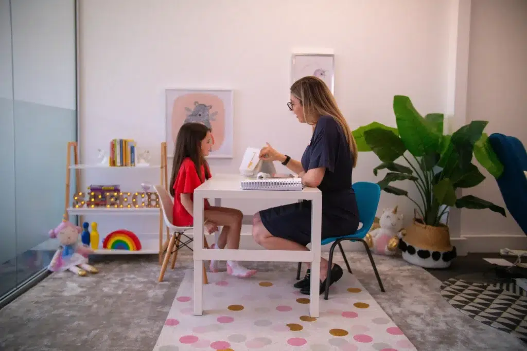 Speech pathologist conducting myofunctional therapy exercises with a young girl in a clinic setting